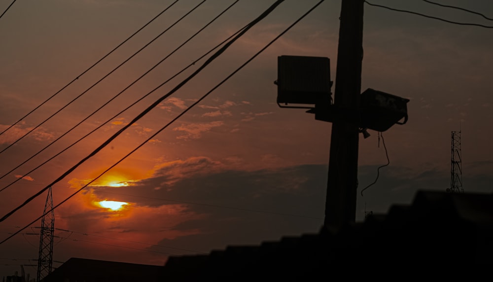 the sun is setting behind a telephone pole