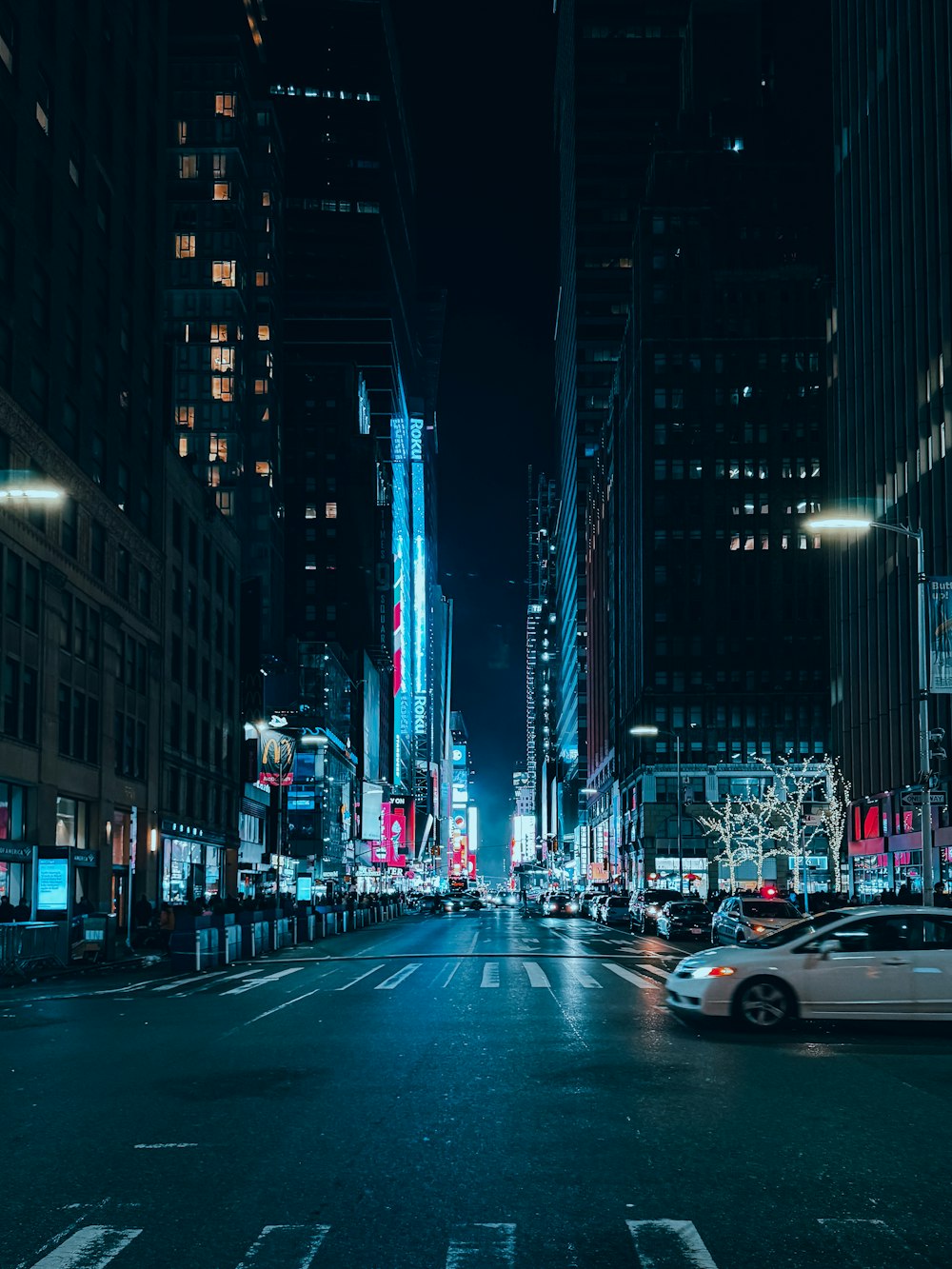 a city street at night with cars driving down it