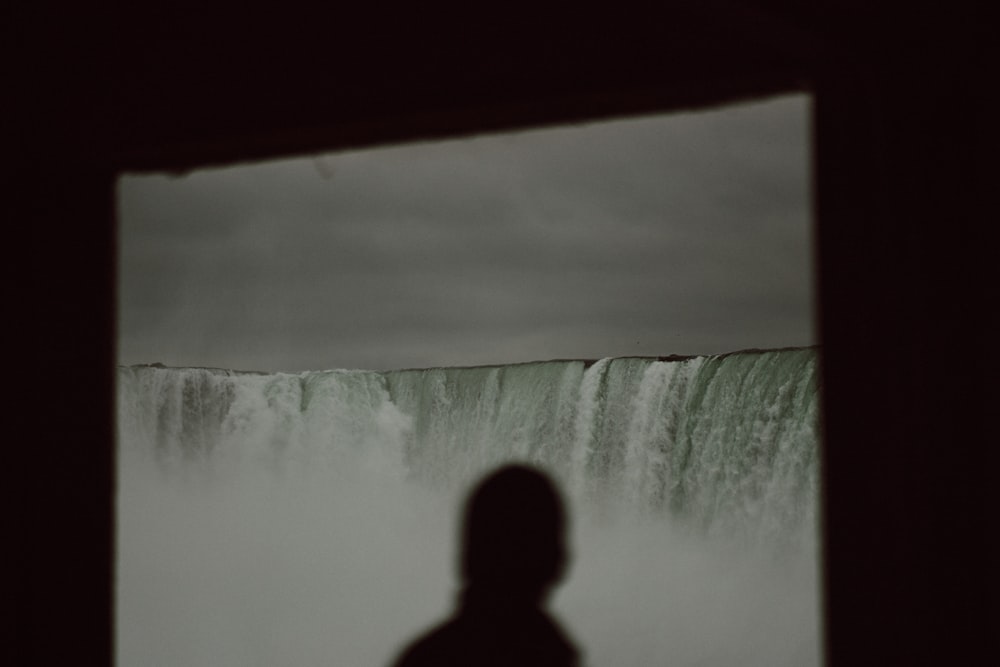 una persona in piedi davanti a una cascata