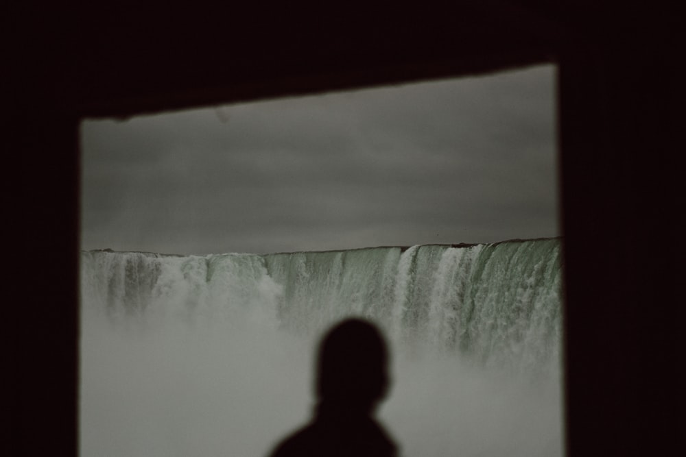 une personne debout devant une chute d’eau