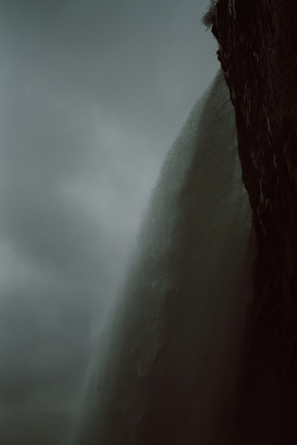 Un hombre de pie en la cima de un acantilado bajo un cielo nublado