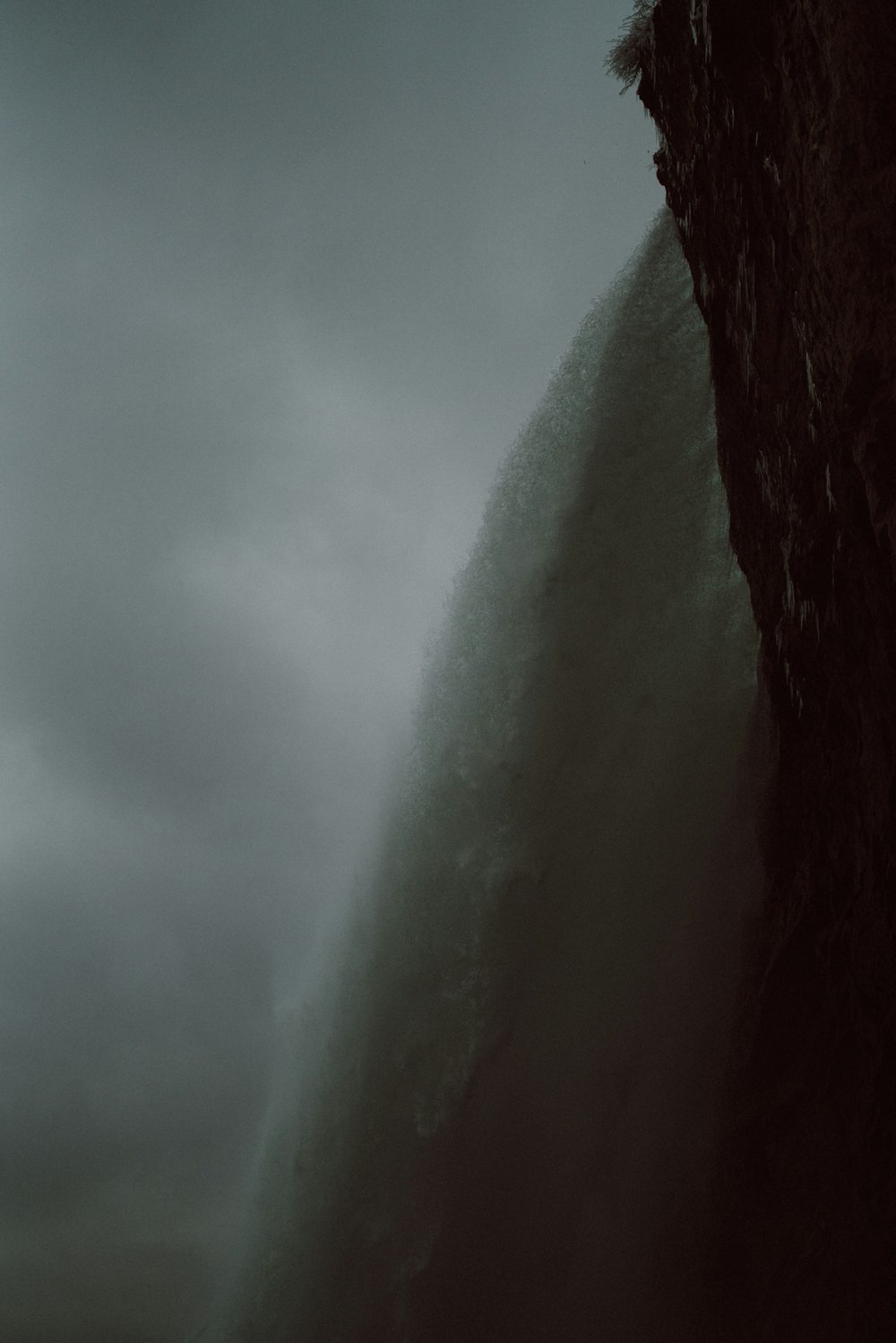 a man standing on top of a cliff under a cloudy sky