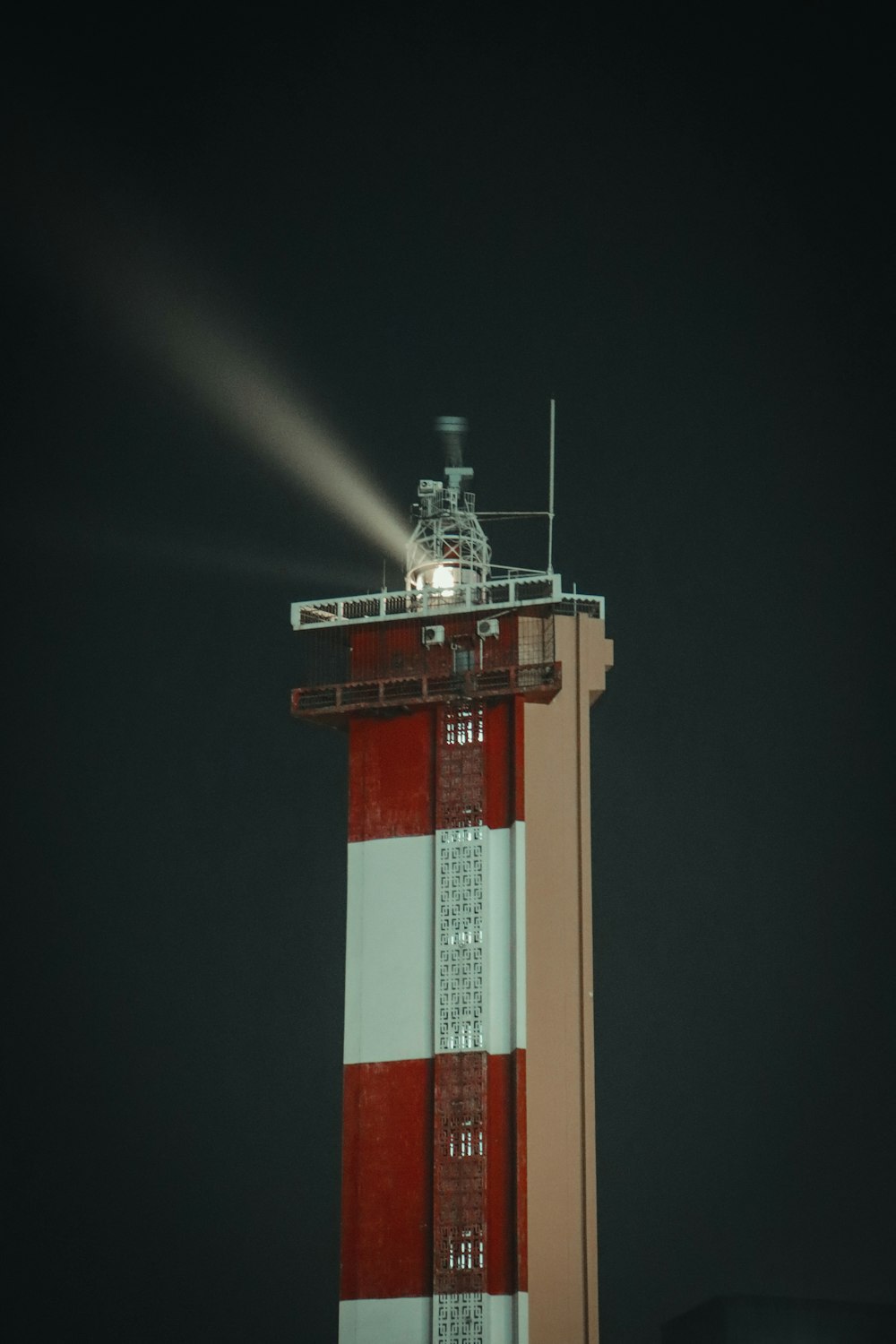 a tall red and white tower with a light on top