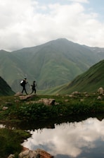 a couple of people walking across a lush green hillside