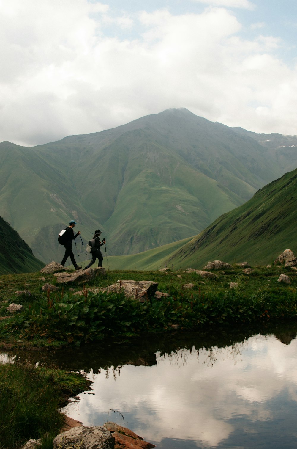 a couple of people walking across a lush green hillside