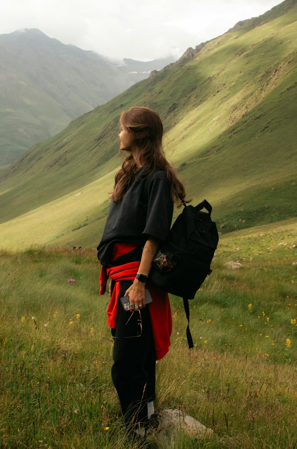 a woman standing in a field with a backpack on her back