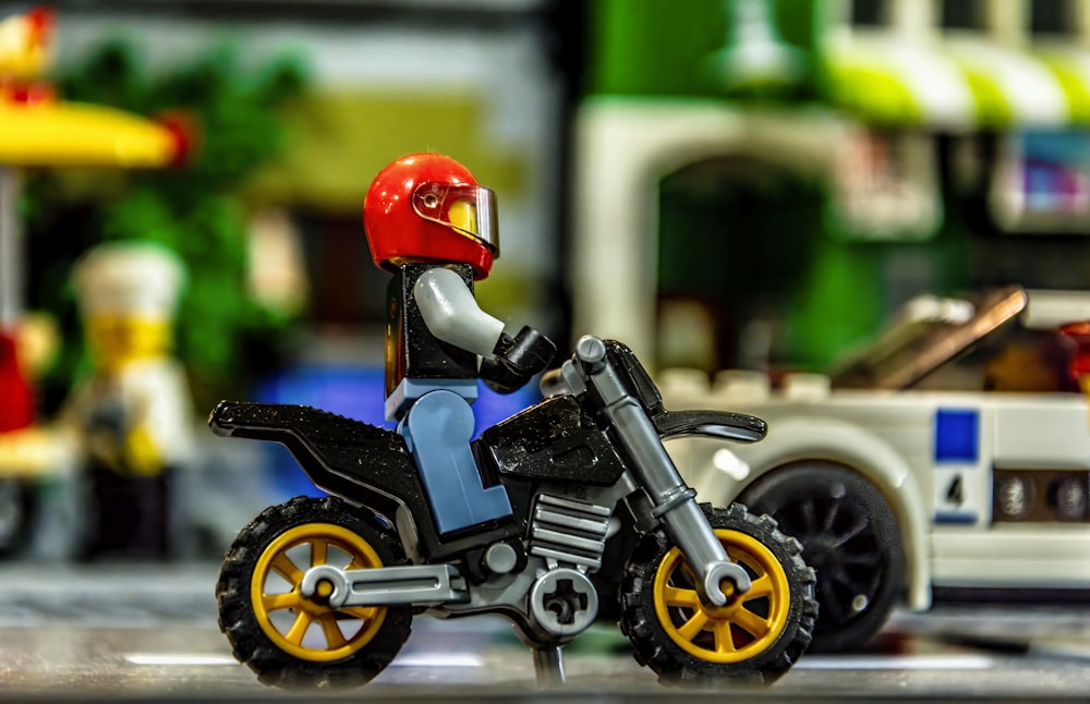 a lego man riding a motorcycle next to a toy car