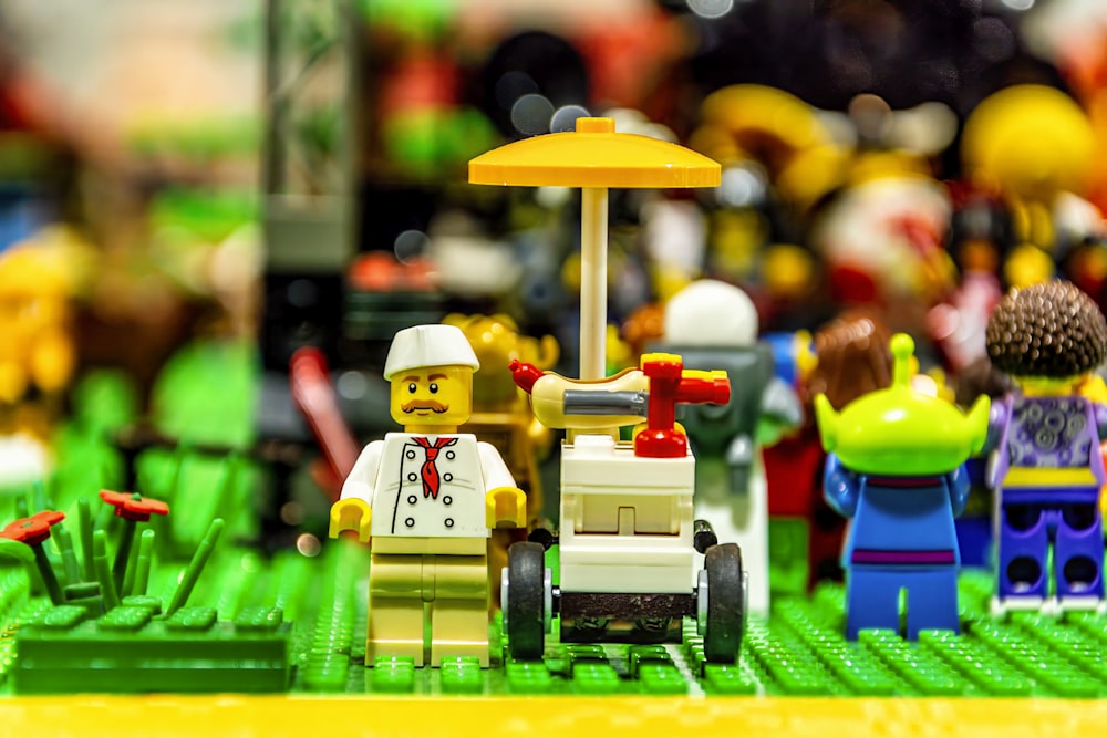 a group of lego people sitting on top of a green field