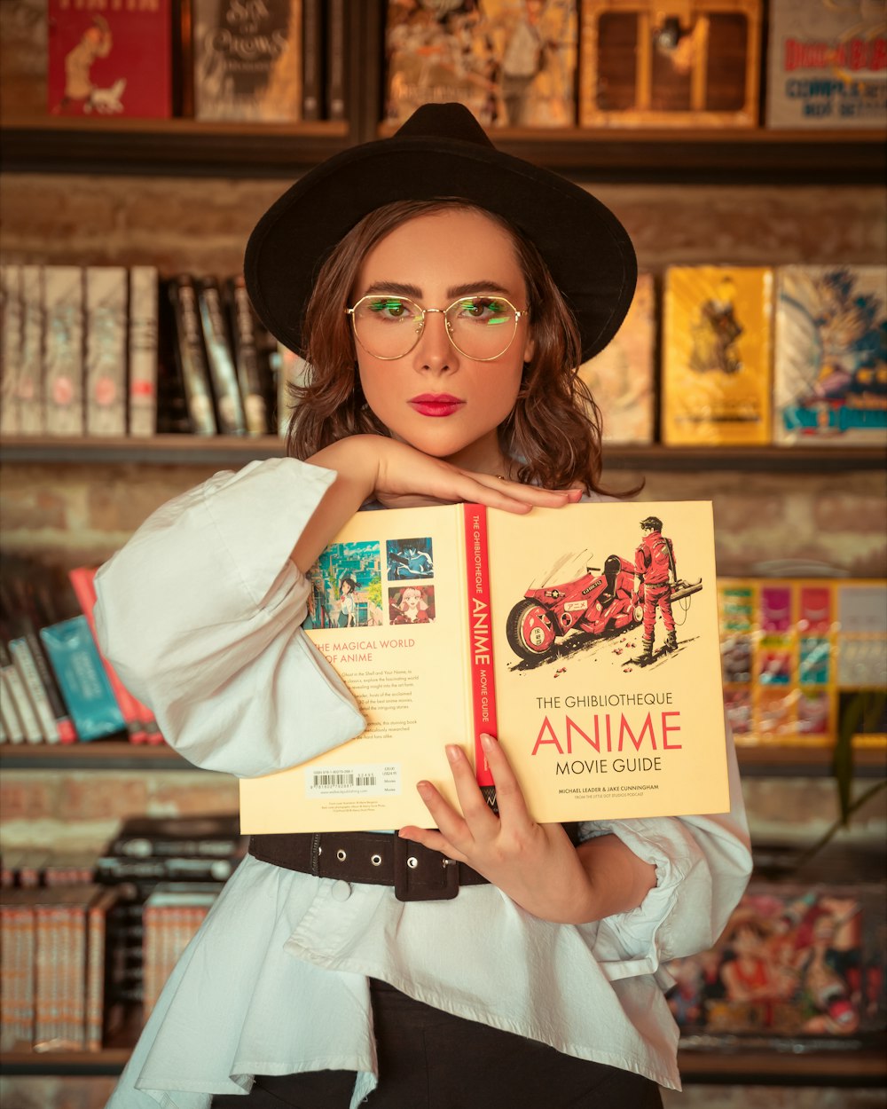 a woman in a hat and glasses holding a book