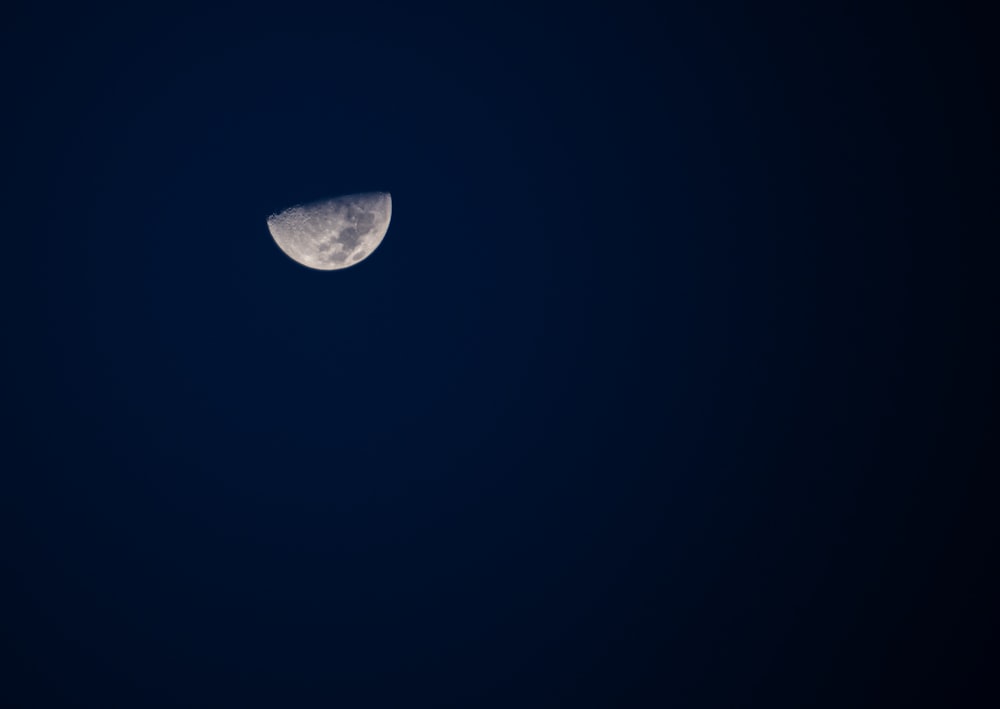 a half moon is seen in the dark sky