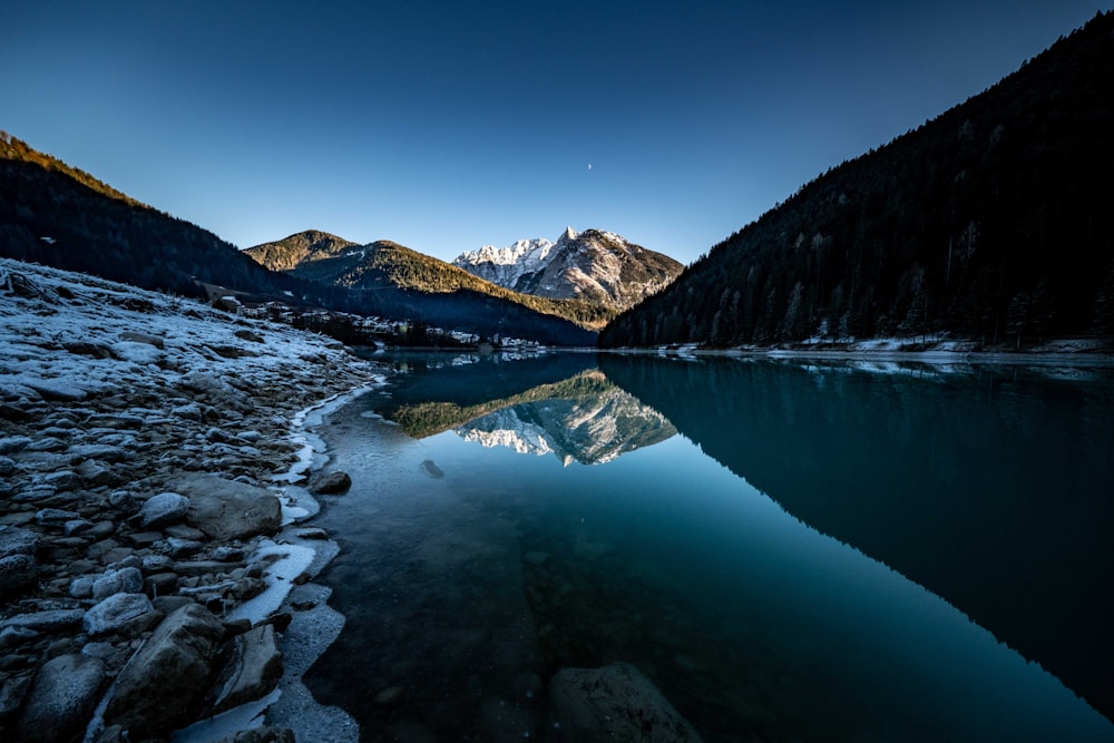 a body of water surrounded by snow covered mountains