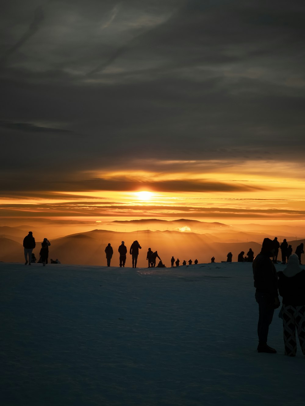 um grupo de pessoas em pé no topo de uma encosta coberta de neve