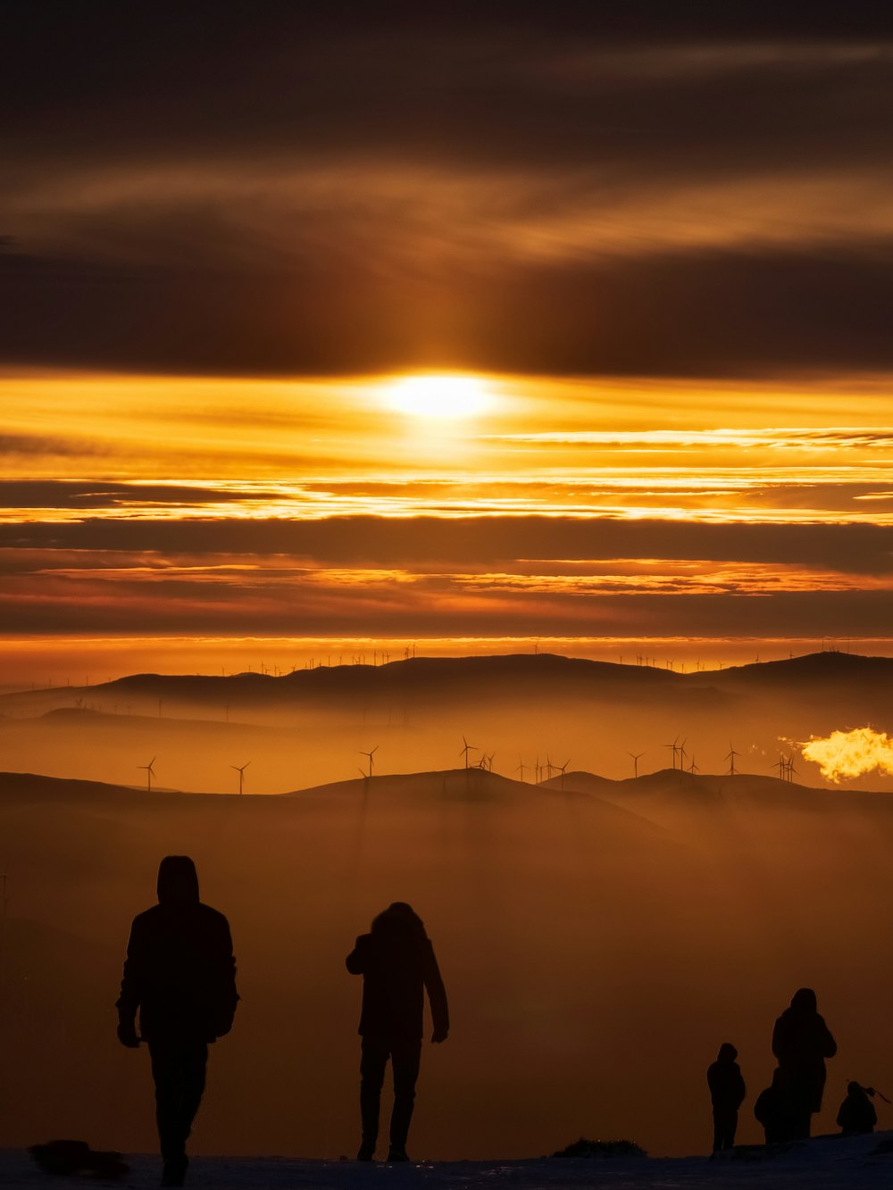 Un grupo de personas de pie en la cima de una ladera cubierta de nieve