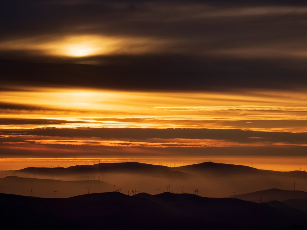 the sun is setting over a mountain range