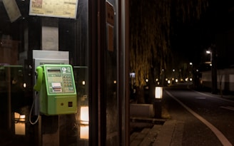a green pay phone sitting on the side of a building