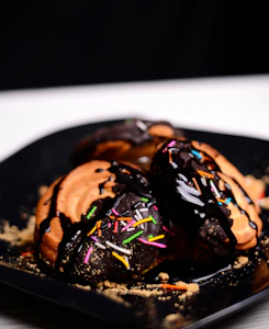 a black plate topped with chocolate covered donuts