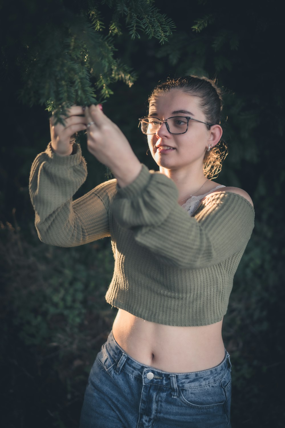 a woman wearing glasses is holding a tree branch