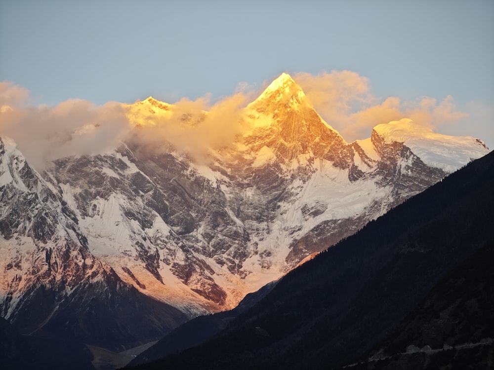 a large mountain covered in snow under a cloudy sky