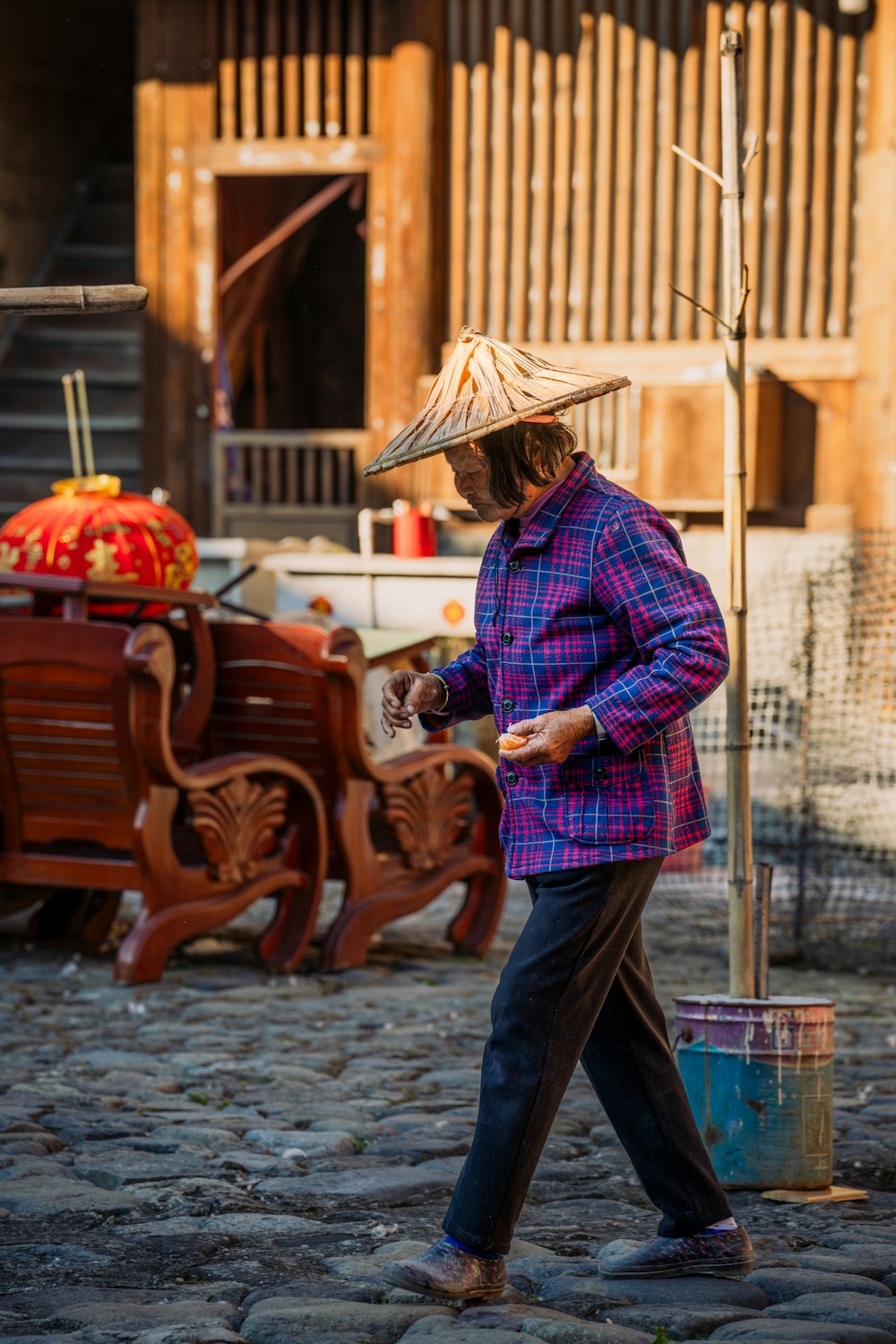 a man with a straw hat walking down a street