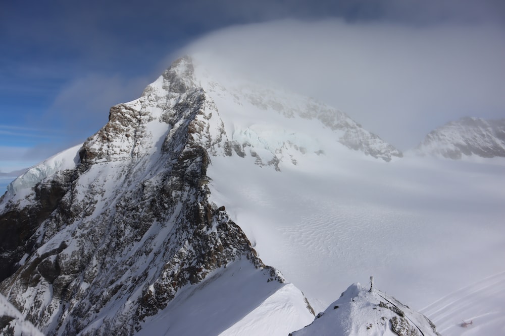 a very tall mountain covered in snow under a cloudy sky