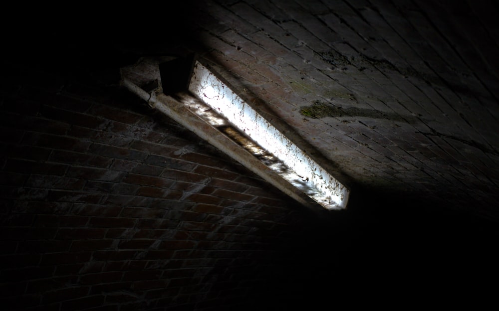 a dark room with a window and a brick wall