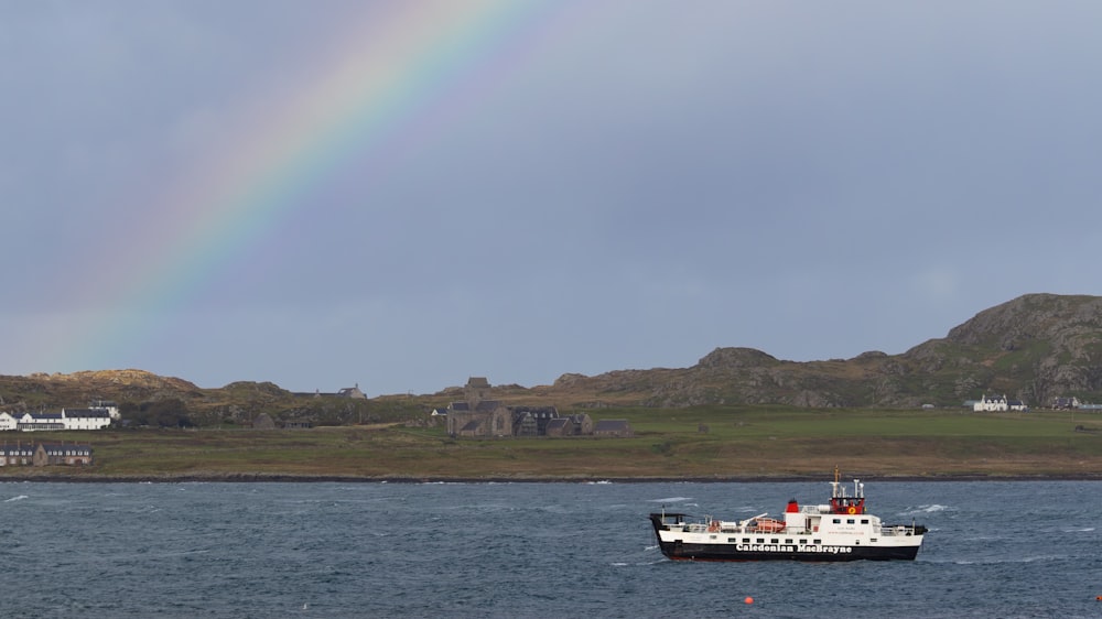 a boat in the water with a rainbow in the background