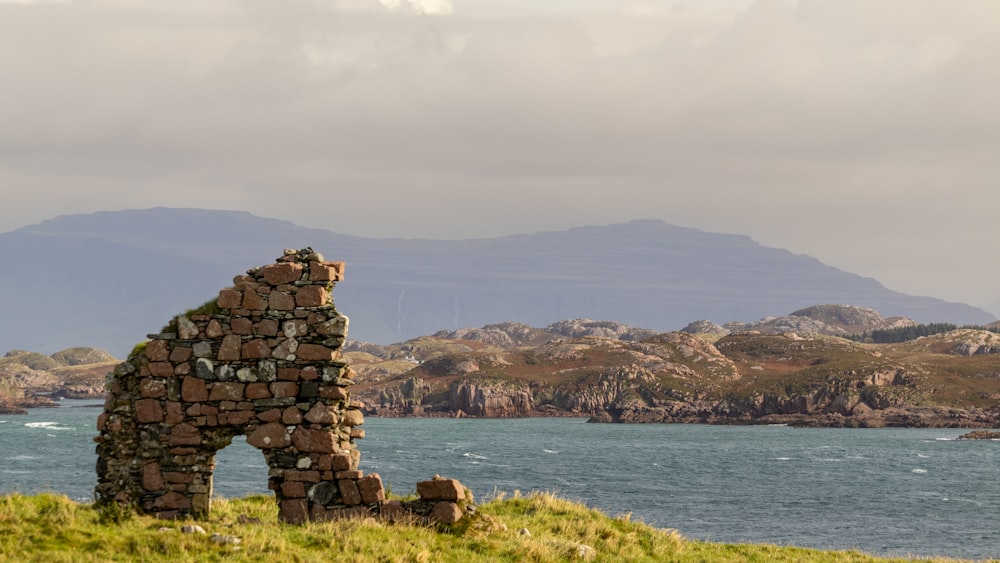 a stone building sitting on top of a lush green hillside