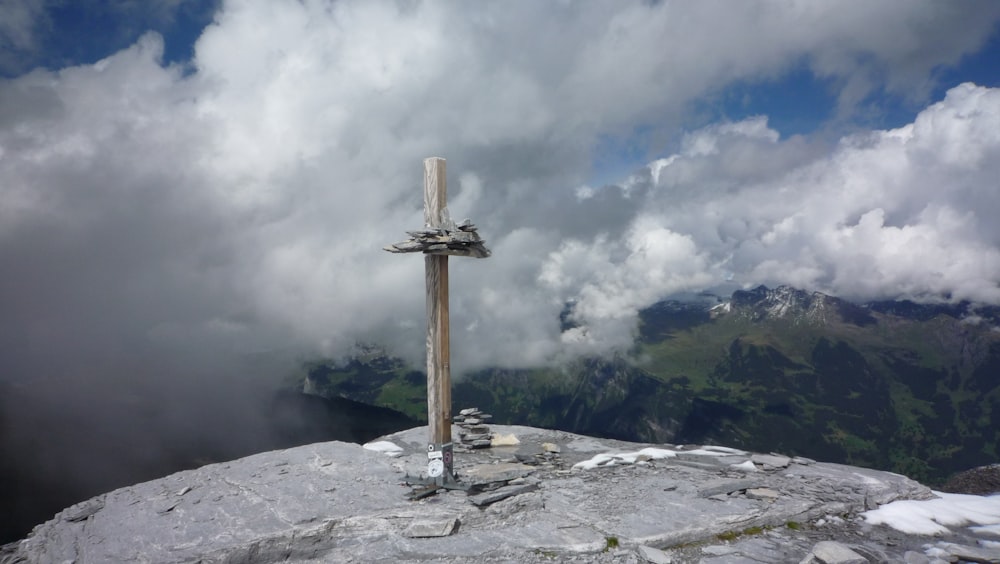 a cross on top of a mountain with clouds in the background