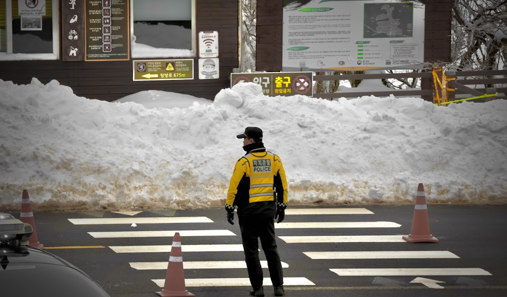 a man in a yellow and black jacket crossing a street