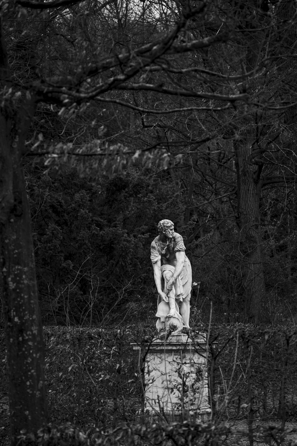 a black and white photo of a statue in the woods