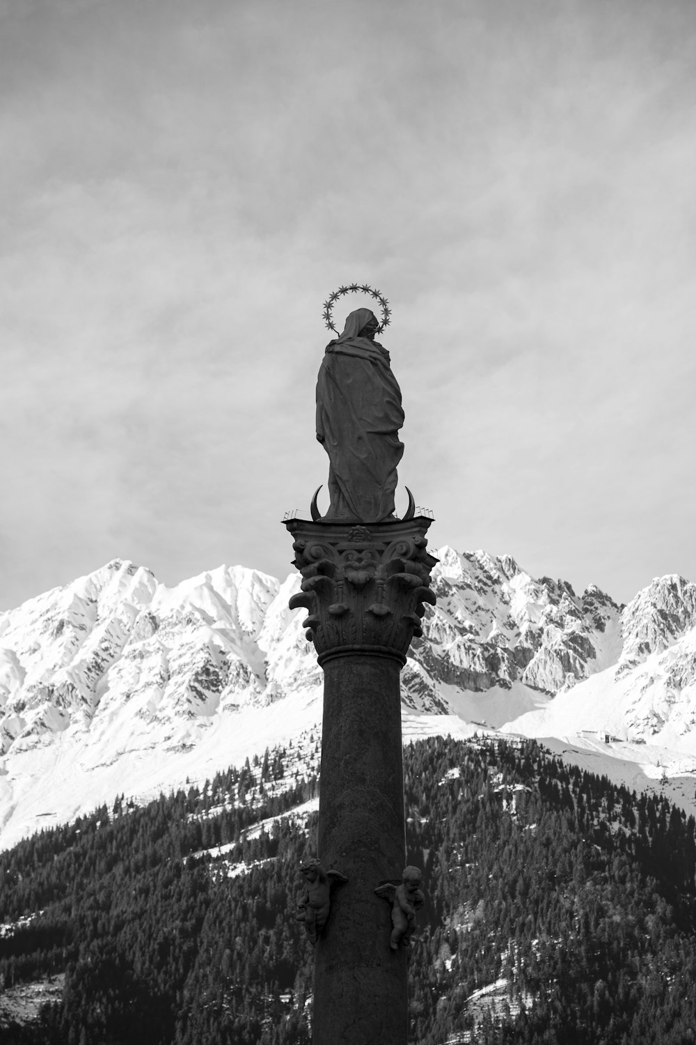 a black and white photo of a statue on top of a pillar