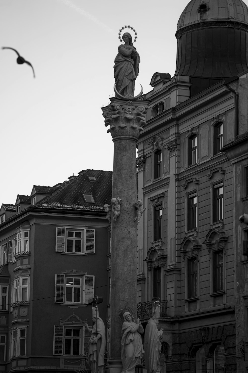 Una foto en blanco y negro de una estatua en la parte superior de un edificio