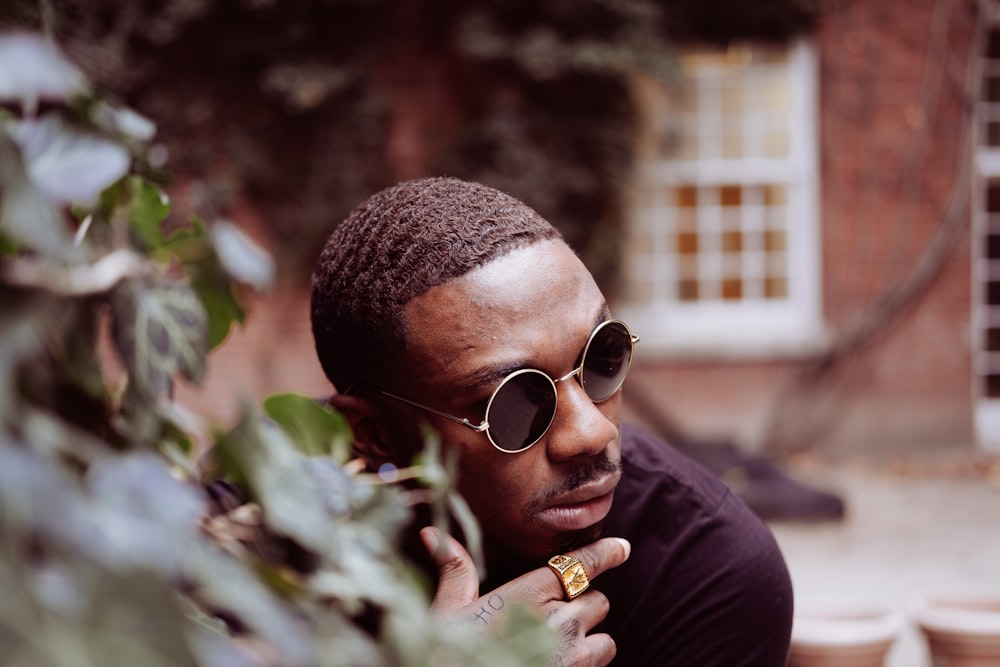 a man wearing sunglasses leaning against a tree