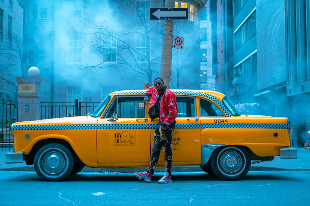 a man standing next to a yellow taxi