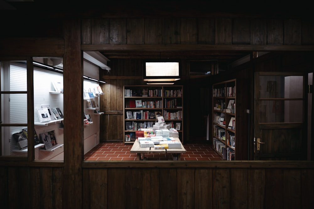a room with a table, bookshelves and a window
