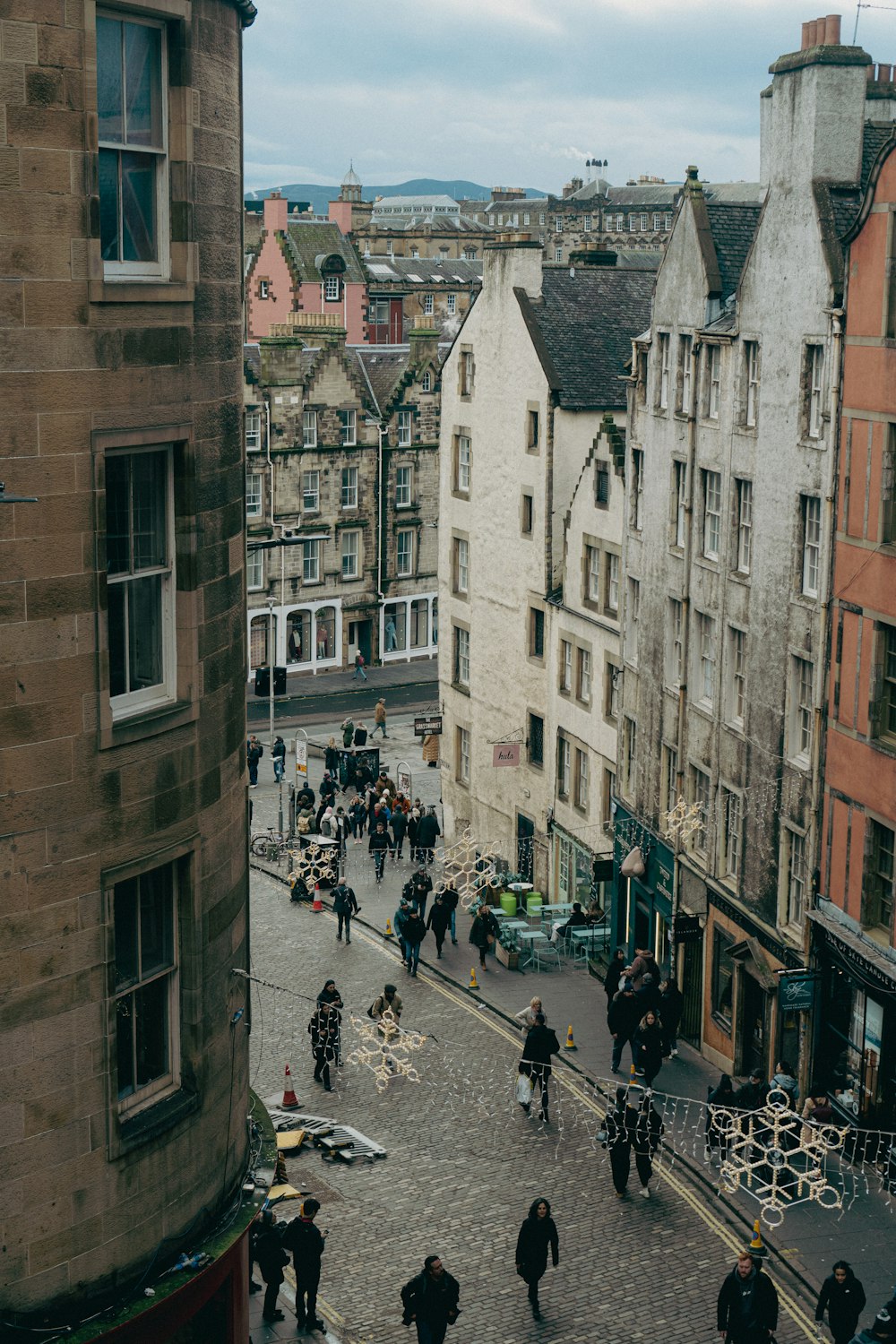 a group of people walking down a street next to tall buildings