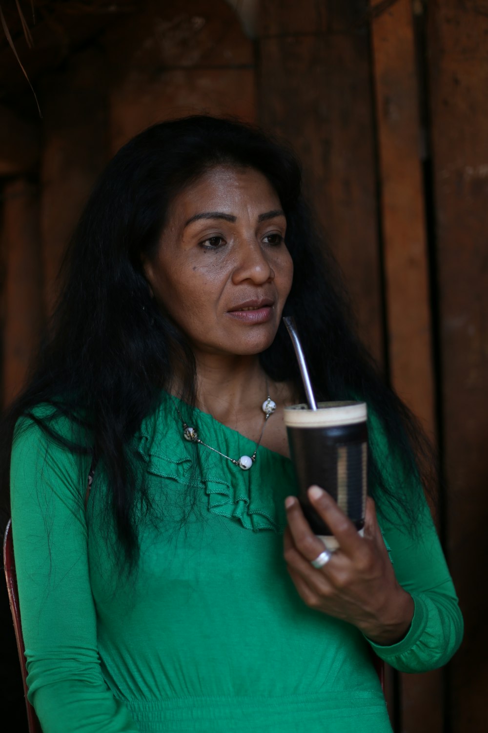 a woman in a green shirt holding a drink