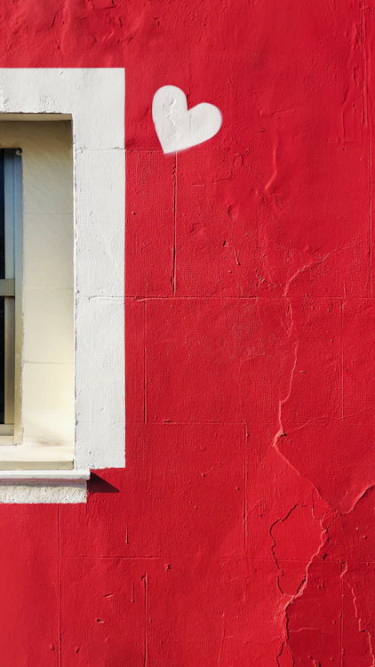 a red wall with a window and a heart painted on it