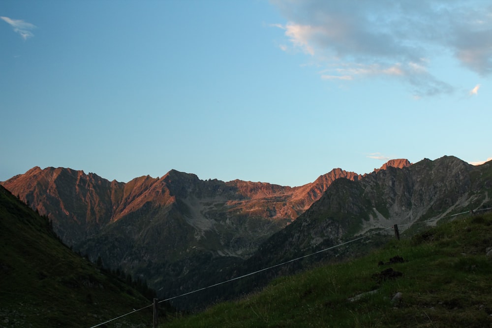 Una vista de una cadena montañosa con una valla en primer plano