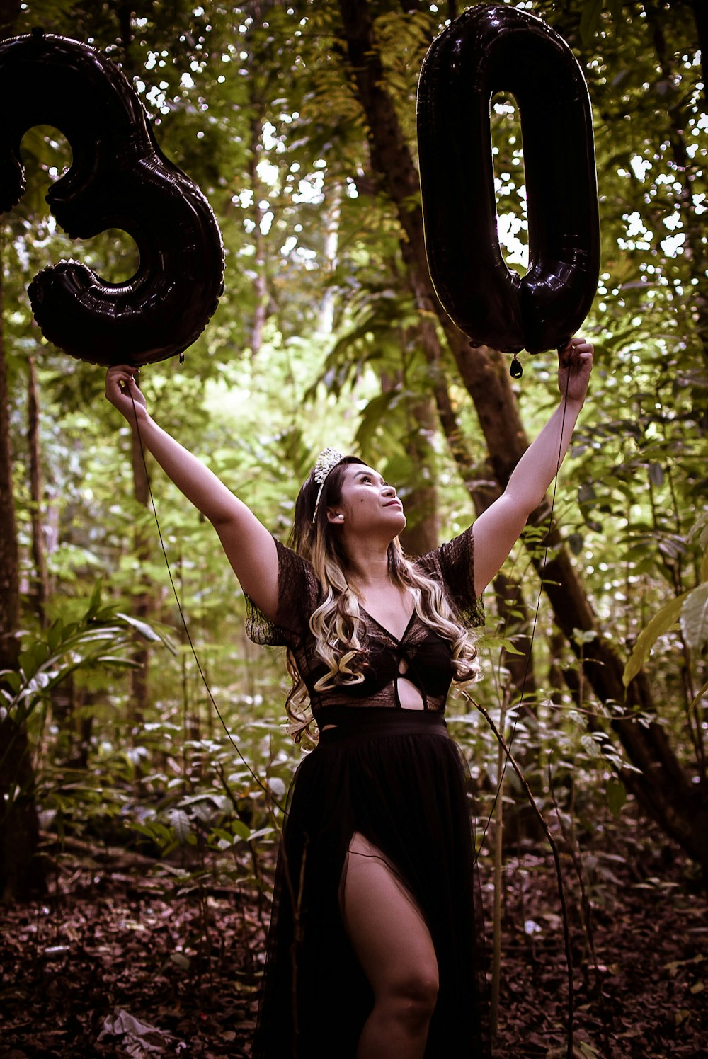 a woman in a black dress holding two large black numbers