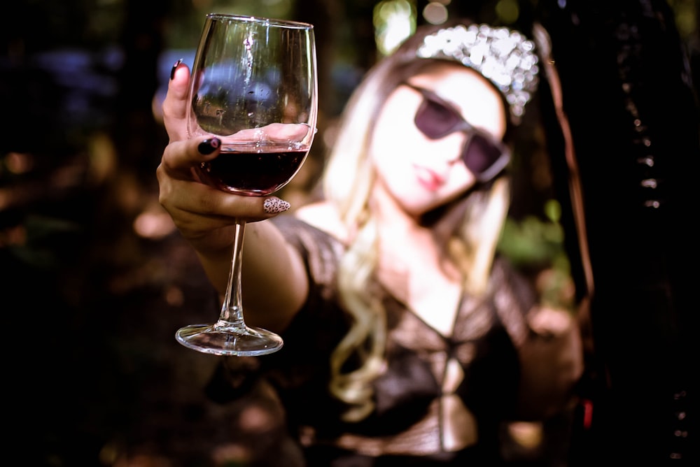 a woman holding a glass of wine in her hand