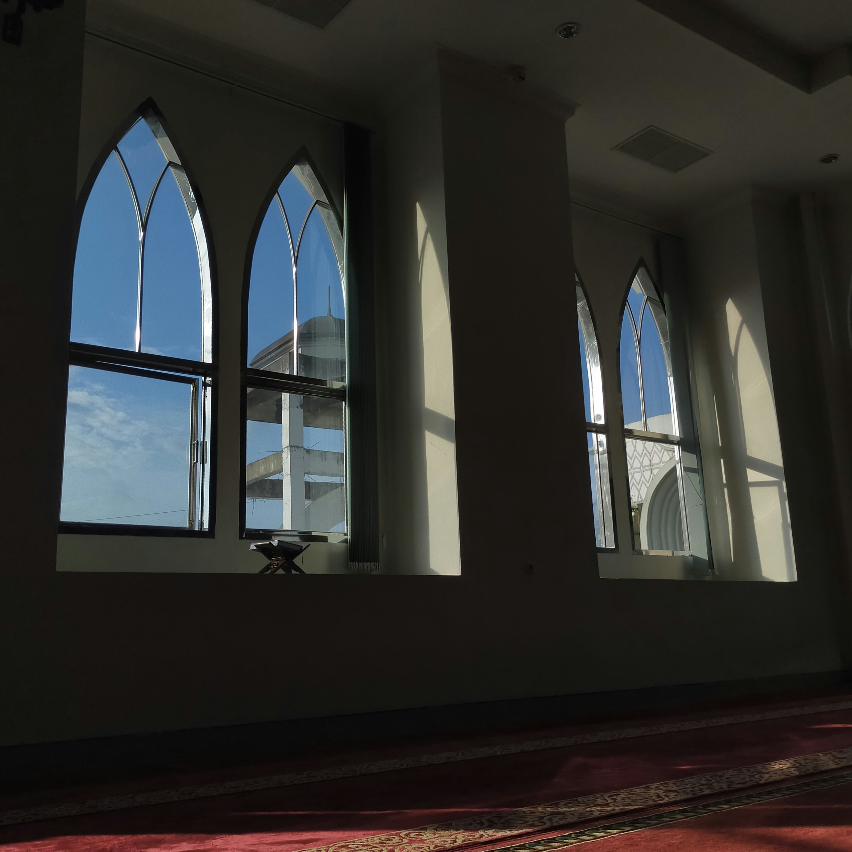 ein Zimmer mit drei Fenstern und einem Teppich auf dem Boden