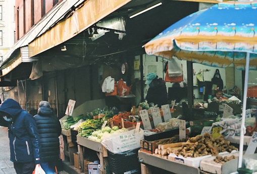 a person walking past a fruit and vegetable stand