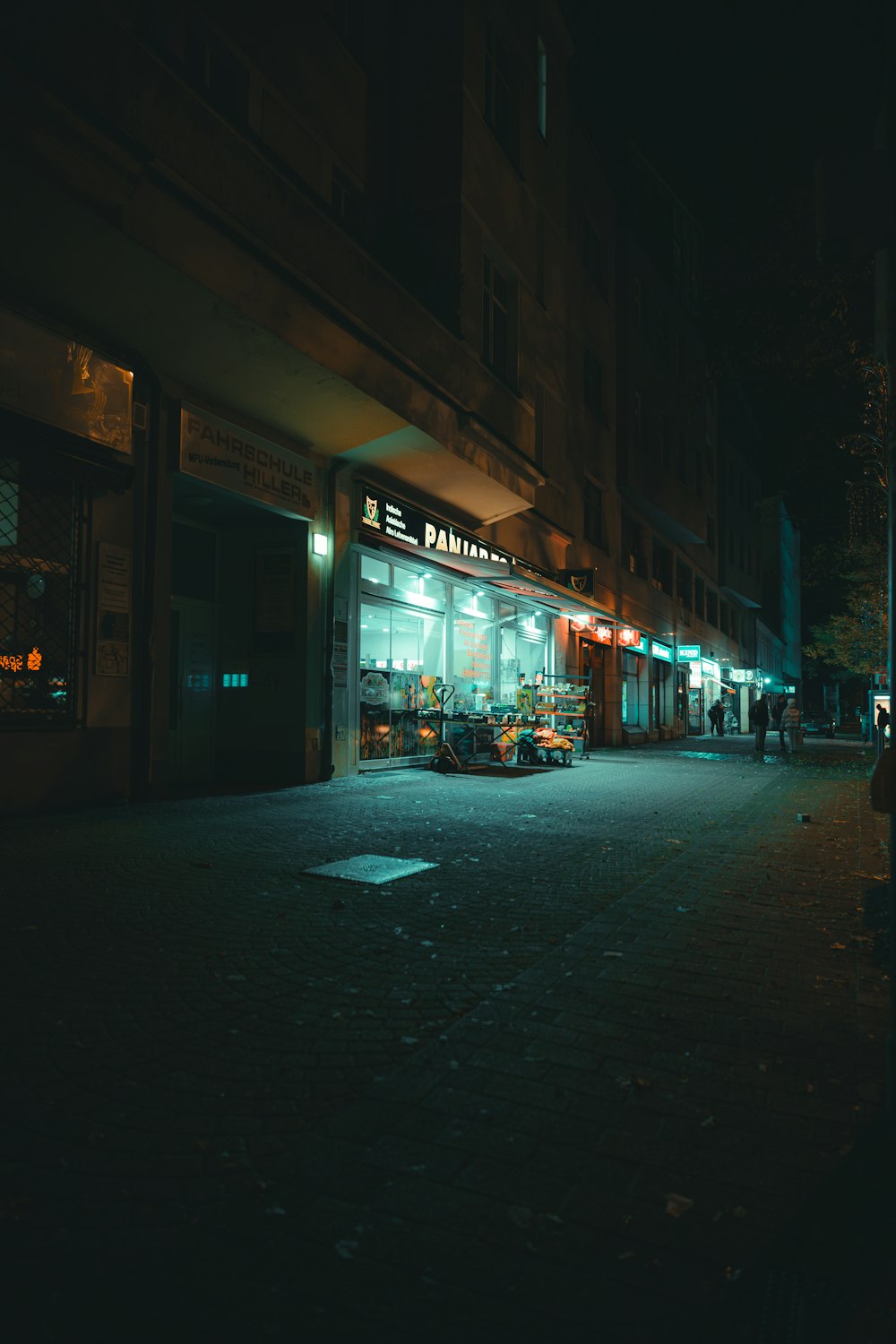 uma rua escura à noite com uma frente de loja iluminada