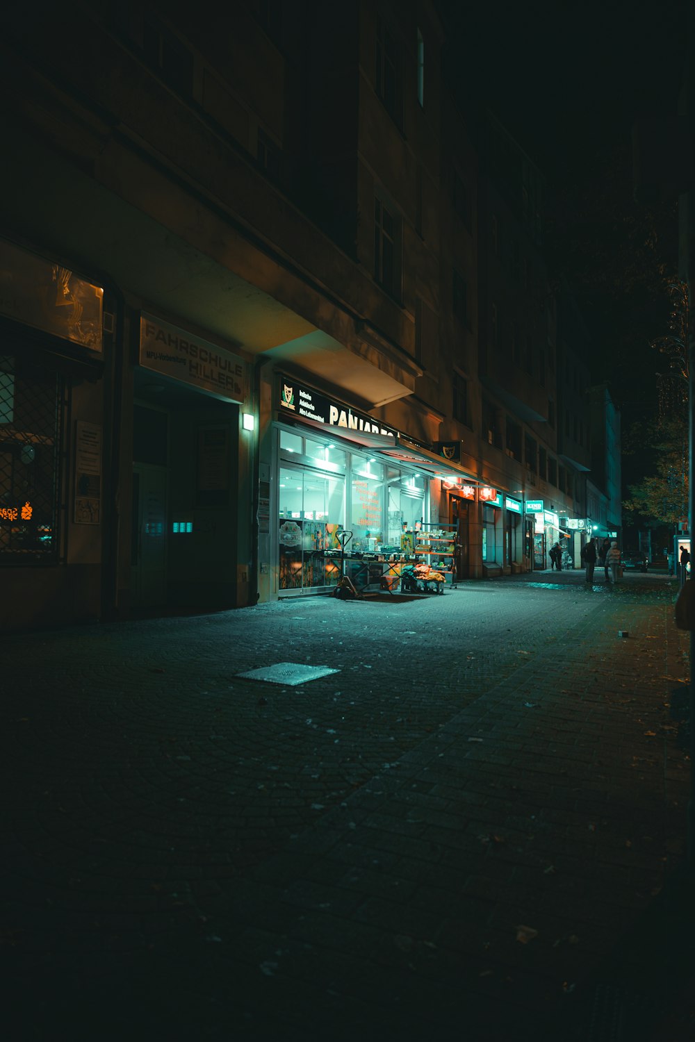 a dark street at night with a store front lit up