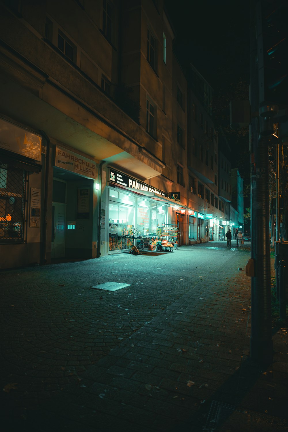 uma rua escura da cidade à noite com uma frente de loja