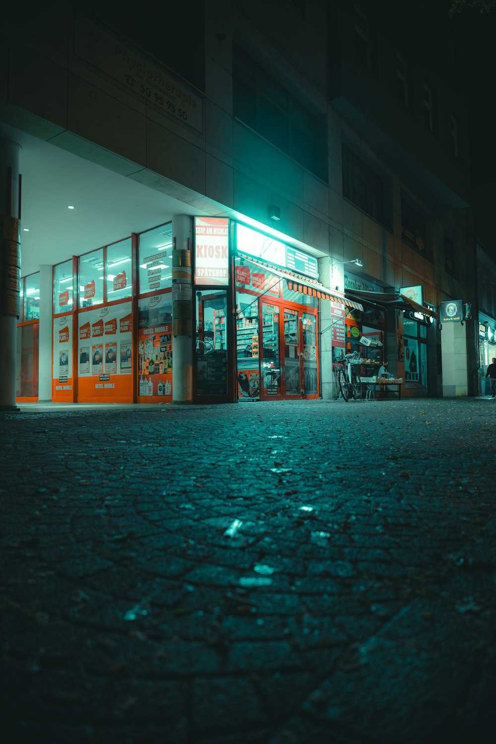 un angolo di strada con un negozio illuminato di notte