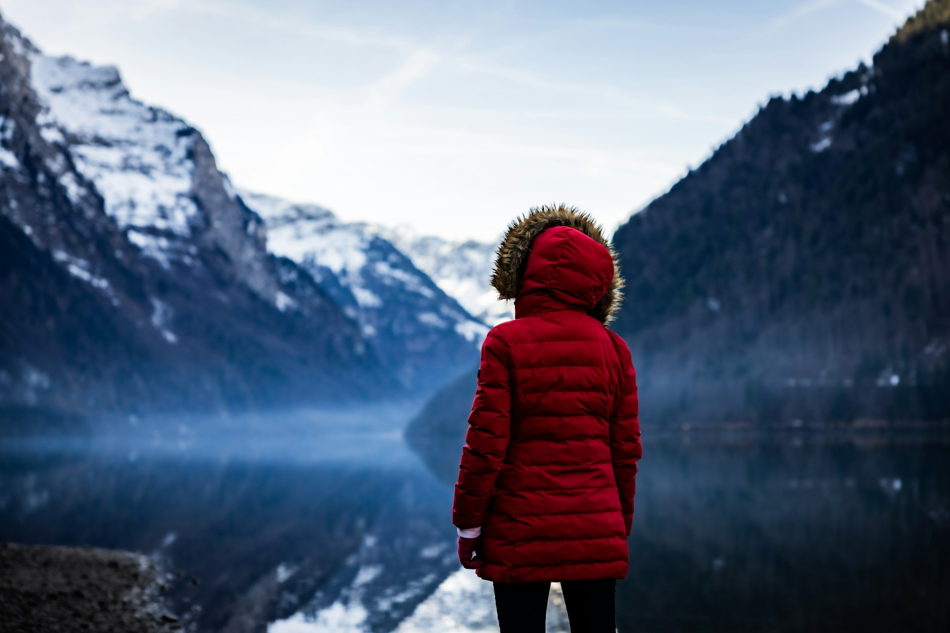 a person in a red jacket looking at a mountain lake