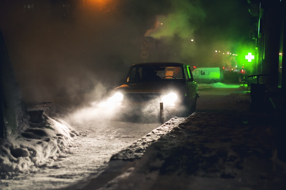 a car driving down a snow covered road at night