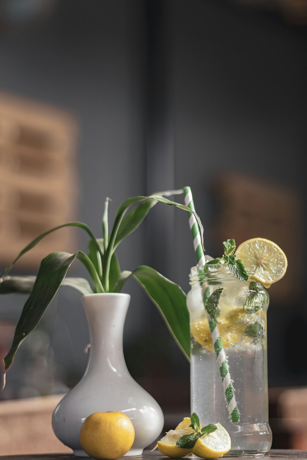 a white vase with lemons and a green plant